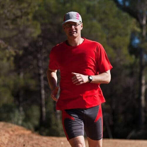 Man running on forest trail in red shirt