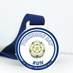 Finishers medal with the illustration of the Yorkshire flower in the centre and the words, "Yorkshire Day" featured along the top and the word "Run" along the bottom