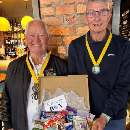 Two men with medals holding gift hamper