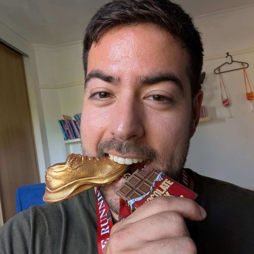 Man biting gold shoe medal indoors
