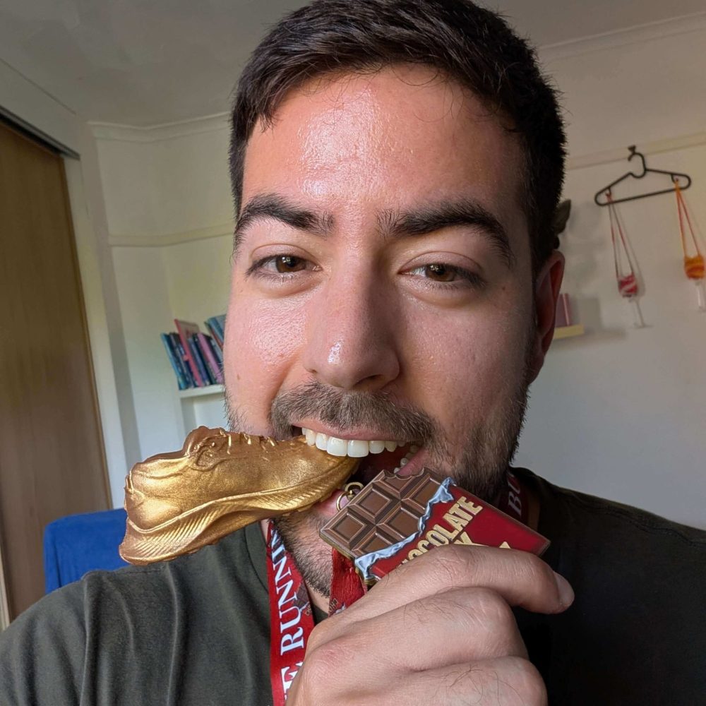 Man biting gold shoe medal indoors